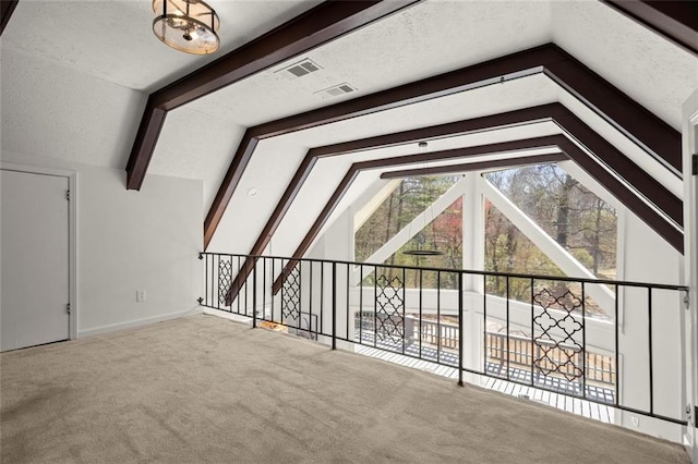 additional living space with lofted ceiling with beams, carpet, visible vents, and a textured ceiling