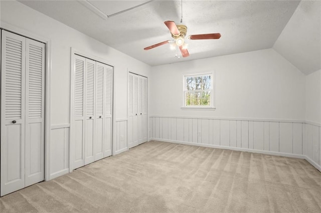 unfurnished bedroom with a textured ceiling, two closets, and carpet flooring