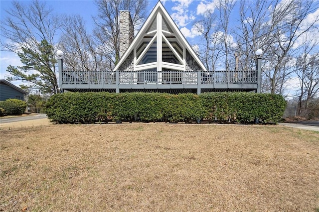 view of front of home featuring a chimney, a front yard, and a wooden deck