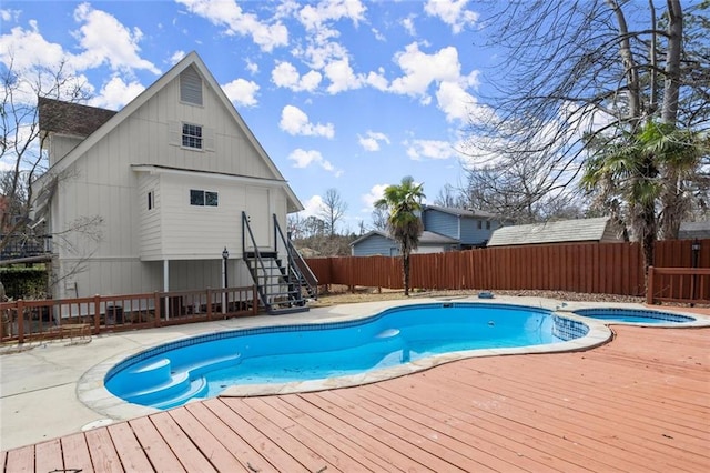 view of swimming pool with a pool with connected hot tub, a fenced backyard, and a wooden deck