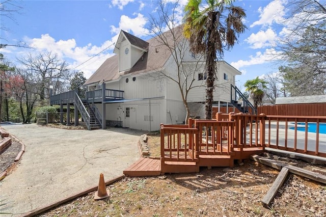 rear view of property featuring a deck, fence, stairway, a fenced in pool, and a patio area