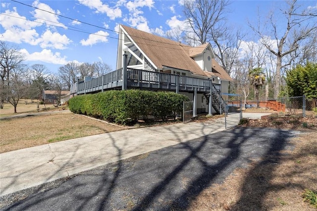 view of home's exterior featuring a gate, fence, a wooden deck, and stairs