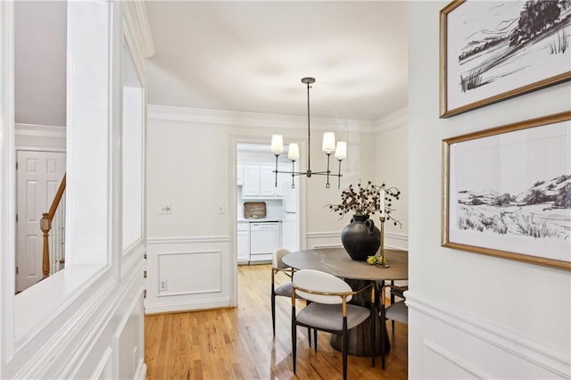 1634 Ponce De Leon Ave NE Unit 514, Atlanta, GA 30307 - dining area with a chandelier, light wood-type flooring, a decorative wall, wainscoting, and crown molding