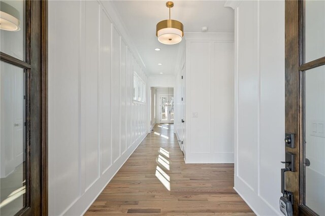 corridor featuring light wood finished floors, a decorative wall, and recessed lighting