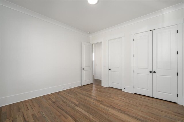 unfurnished bedroom with baseboards, wood finished floors, and crown molding