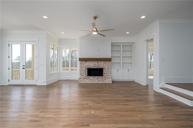 unfurnished living room featuring a brick fireplace, ornamental molding, wood finished floors, and recessed lighting