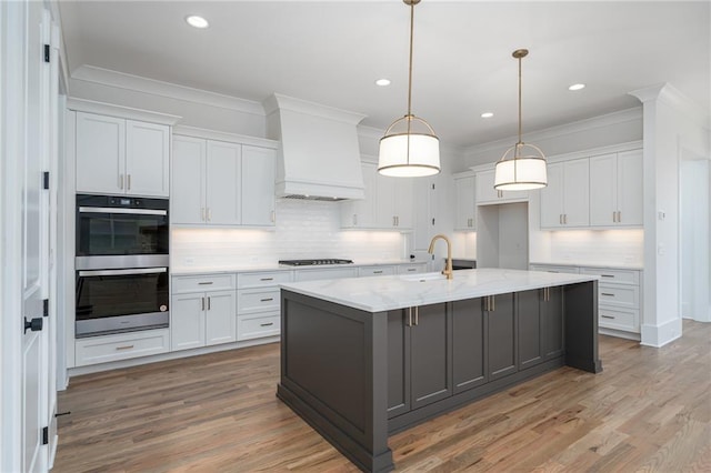 kitchen with stainless steel double oven, a sink, white cabinetry, ornamental molding, and custom range hood