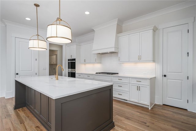 kitchen featuring stainless steel appliances, custom range hood, ornamental molding, white cabinets, and wood finished floors