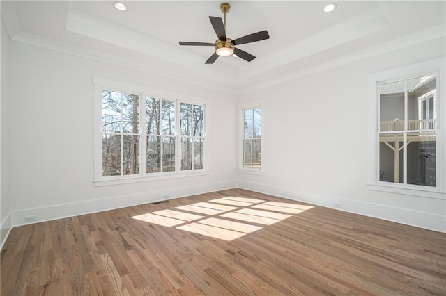 unfurnished room featuring baseboards, a tray ceiling, wood finished floors, and recessed lighting