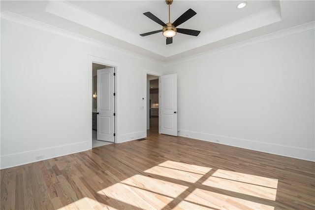 empty room featuring crown molding, a tray ceiling, and wood finished floors