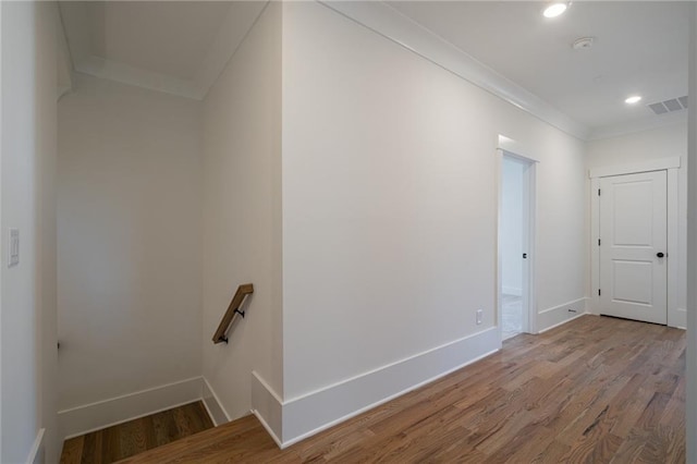 interior space featuring baseboards, wood finished floors, visible vents, and crown molding