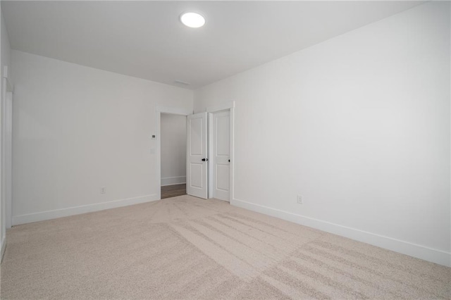 unfurnished room with light colored carpet and baseboards