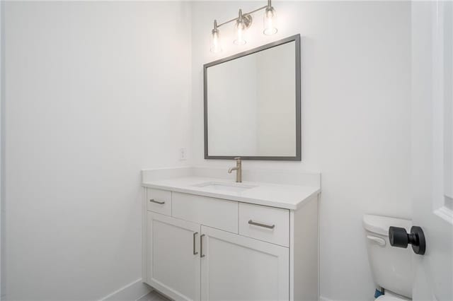 bathroom featuring toilet, vanity, and baseboards