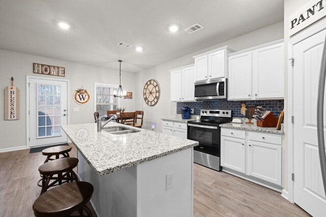 2046 Westbrook Rd, Commerce, GA 30530 - kitchen with stainless steel appliances, a sink, a breakfast bar, a kitchen island with sink, and decorative backsplash