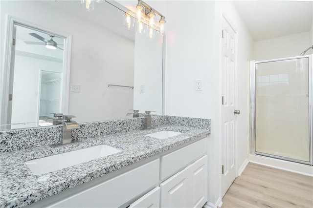 bathroom featuring a shower with shower door, hardwood / wood-style flooring, vanity, and ceiling fan