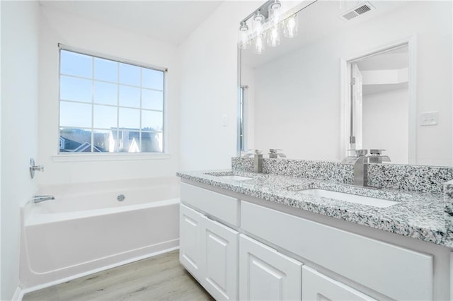 bathroom featuring hardwood / wood-style flooring, a washtub, and vanity