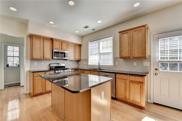 kitchen with appliances with stainless steel finishes, a sink, plenty of natural light, a kitchen island, and recessed lighting