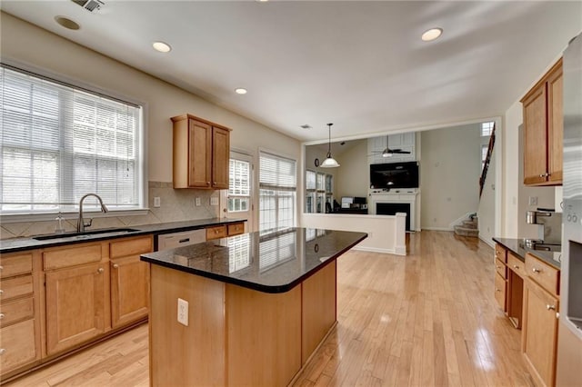 kitchen with a sink, a kitchen island, a fireplace, open floor plan, and tasteful backsplash