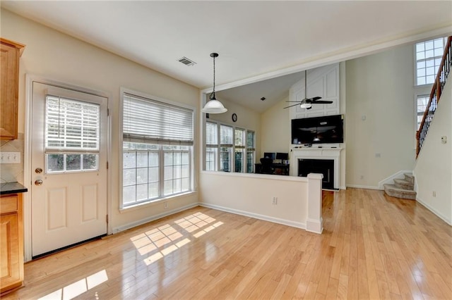 kitchen with light wood-style flooring, a fireplace, open floor plan, baseboards, and lofted ceiling
