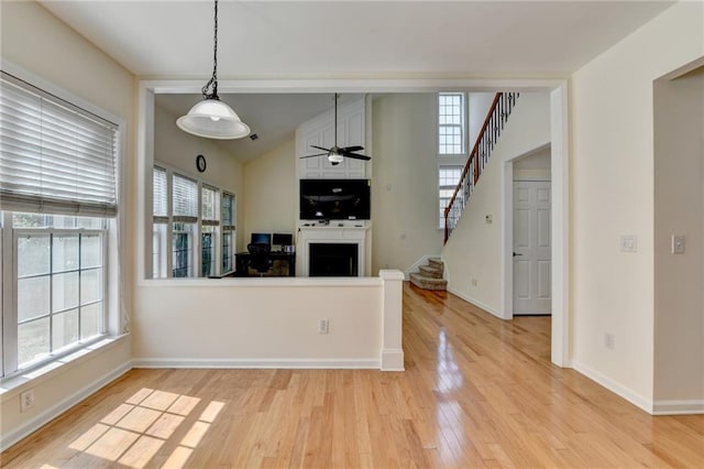 kitchen featuring light wood finished floors, a ceiling fan, a fireplace, baseboards, and lofted ceiling