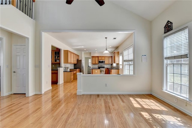 unfurnished living room featuring light wood-type flooring, ceiling fan, lofted ceiling, and baseboards