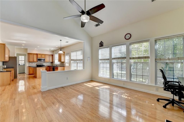 unfurnished living room with plenty of natural light, light wood-style floors, ceiling fan, baseboards, and lofted ceiling