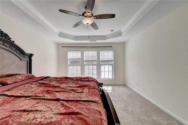 carpeted bedroom featuring a tray ceiling, crown molding, baseboards, and ceiling fan