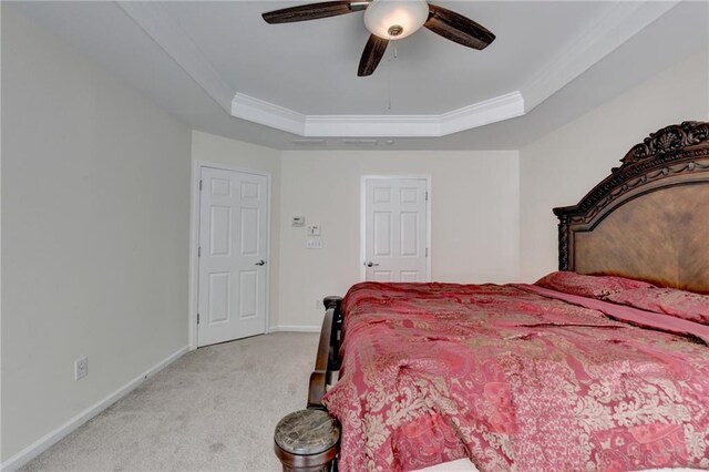 bedroom with light colored carpet, a tray ceiling, baseboards, ornamental molding, and ceiling fan