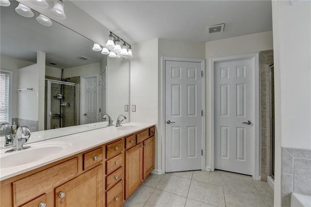 bathroom with tile patterned flooring, a shower stall, and double vanity