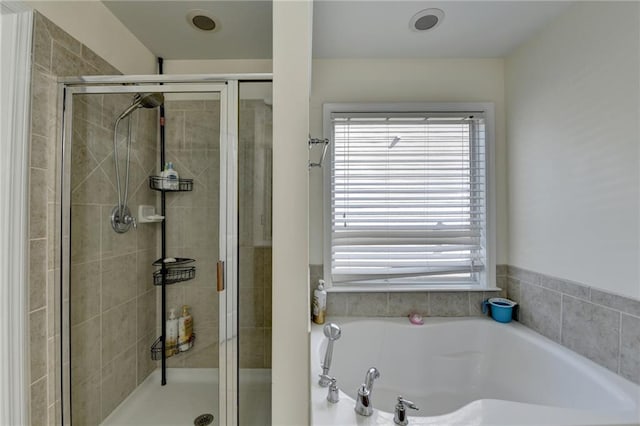 bathroom with healthy amount of natural light, a stall shower, and a garden tub