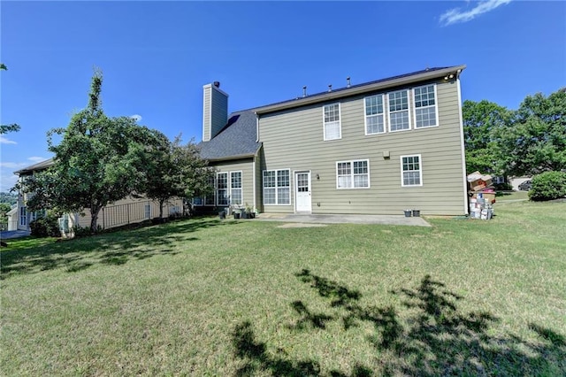 rear view of house featuring a chimney, a patio area, and a yard