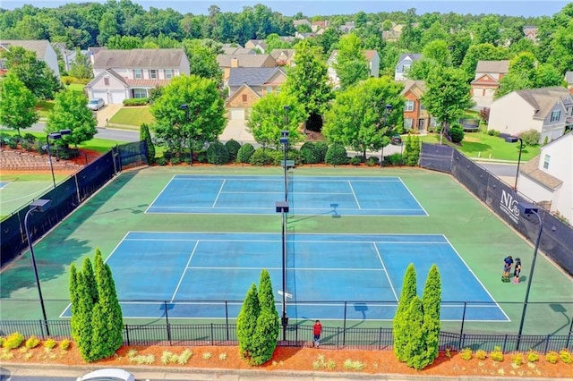 view of tennis court featuring fence and a residential view