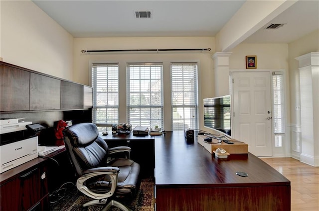 office space featuring plenty of natural light, light wood finished floors, and decorative columns