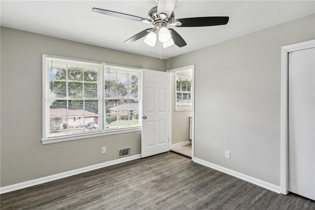 unfurnished bedroom featuring dark wood-type flooring, ceiling fan, and multiple windows