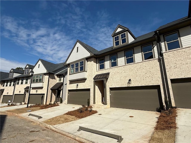 townhome / multi-family property with a garage, a residential view, concrete driveway, and brick siding