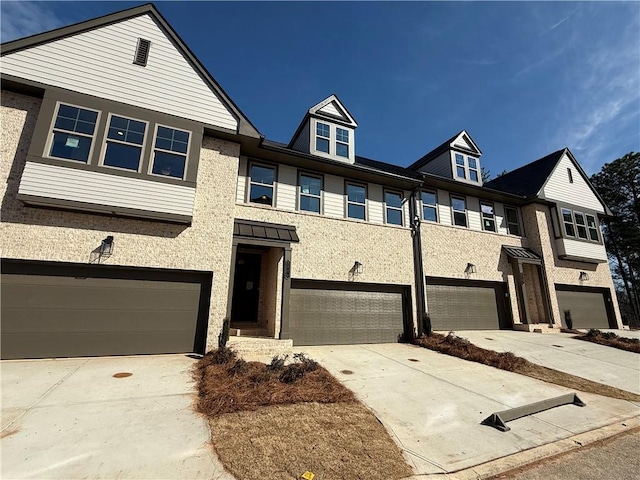 multi unit property featuring an attached garage, concrete driveway, and brick siding