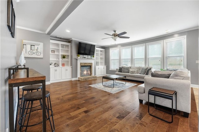 living room with wood finished floors, ornamental molding, and a fireplace