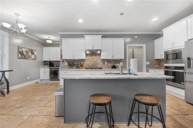 kitchen featuring visible vents, under cabinet range hood, beverage cooler, stainless steel appliances, and a sink