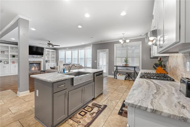 kitchen with gray cabinetry, a sink, stainless steel appliances, crown molding, and a brick fireplace