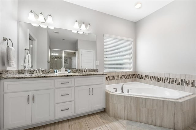 full bathroom featuring a shower stall, a bath, double vanity, and a sink