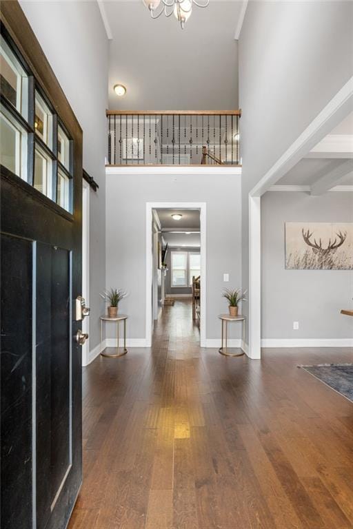 entrance foyer featuring a notable chandelier, baseboards, a high ceiling, and wood finished floors