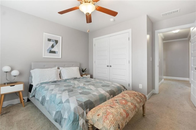 bedroom with visible vents, a closet, baseboards, light colored carpet, and ceiling fan