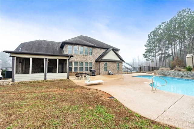 rear view of property featuring a lawn, fence, a sunroom, a fenced in pool, and a patio area