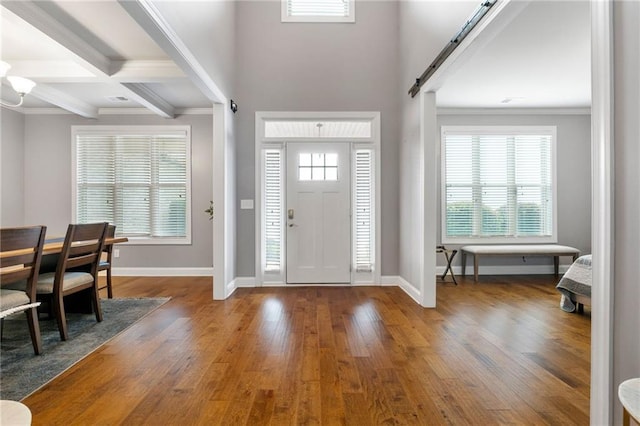 entrance foyer featuring beam ceiling, visible vents, a healthy amount of sunlight, and wood-type flooring