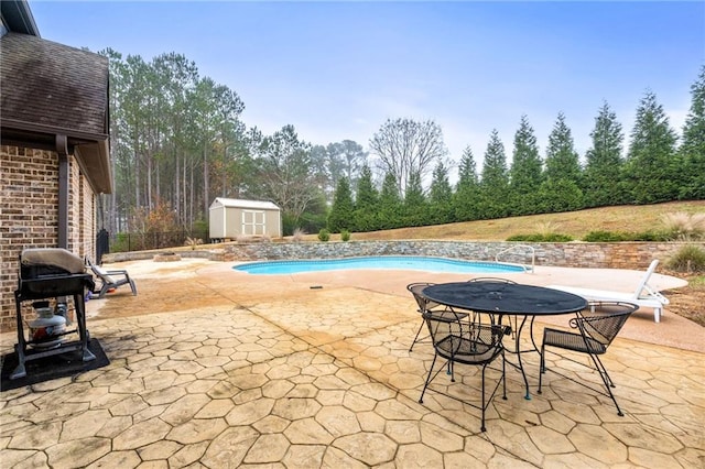 view of swimming pool featuring a fenced in pool, a shed, an outdoor structure, grilling area, and a patio area