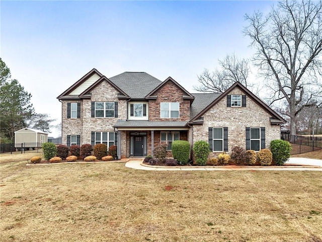 craftsman inspired home featuring brick siding, a front lawn, and fence