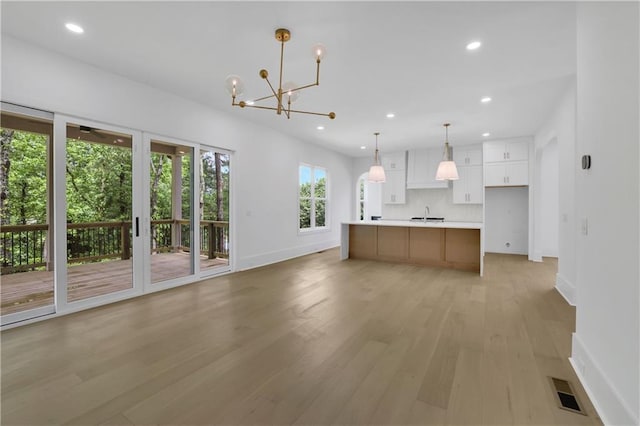 380 Hillcrest View Dr, Suwanee, GA 30024 - kitchen featuring baseboards, a chandelier, light wood-style flooring, white cabinetry, and light countertops