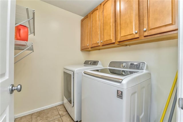 clothes washing area featuring cabinets, light tile patterned flooring, and washer and dryer