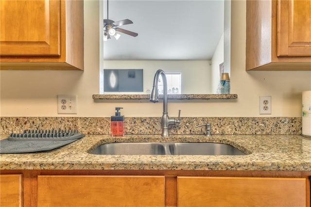 interior details with sink, light stone countertops, and ceiling fan