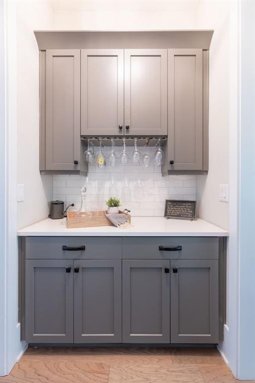 bar featuring tasteful backsplash and gray cabinetry